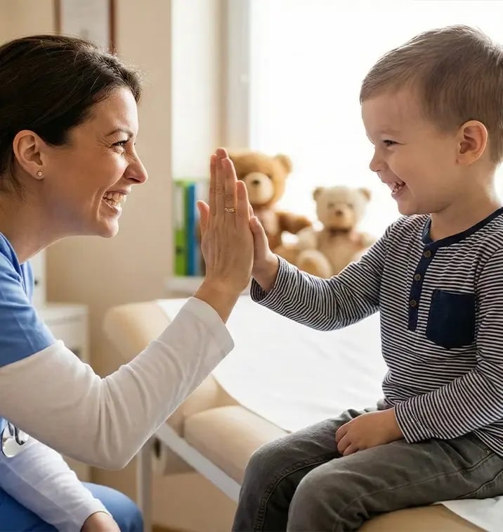 Healthcare provider giving a high-five to a smiling child during a pediatric visit.