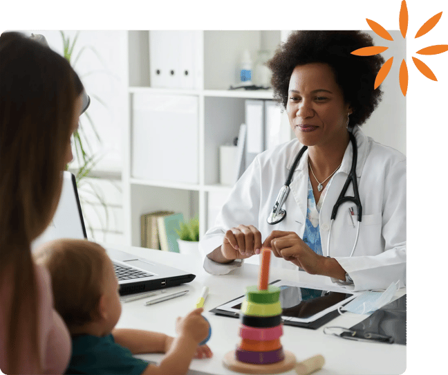 Healthcare provider speaking with a parent and child during a pediatric visit.