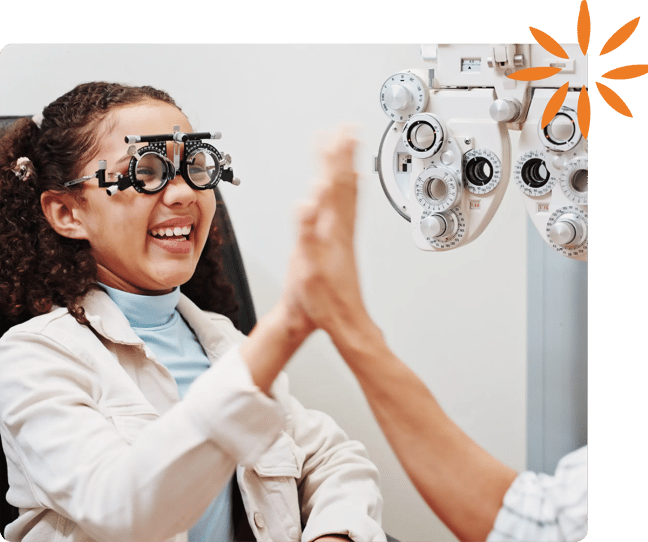 Smiling child wearing vision testing lenses and high-fiving a healthcare provider.