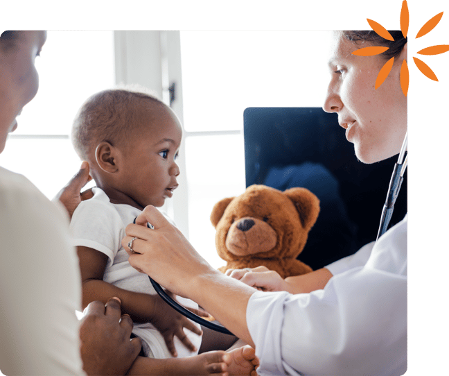 Healthcare provider examining a baby while a parent looks on during a pediatric visit.